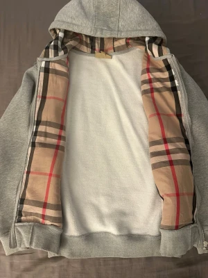 Burberry hoodie - Snygg grå zip-hoodie från Burberry. Har använts fåtal gånger. Den sitter för tajt på mig så den har bara legat i garderoben. Den är ganska tjock för att vara en luvtröja så för sena sommarkvällar är den här perfekt🙌🏻 skriv vid intresse, fler bilder kan alltid fixas. Priset kan diskuteras vid snabb affär🙏🏻
