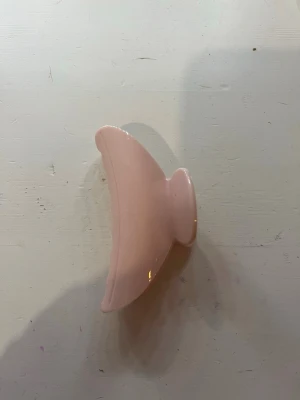 Ljusrosa hårklämma i plast  - Snygg ljusrosa hårklämma i plast med klassisk form och breda taggar som håller håret på plats. Perfekt för att snabbt sätta upp håret i en trendig look. Enkel att matcha med olika stilar och passar både långt och kort hår.