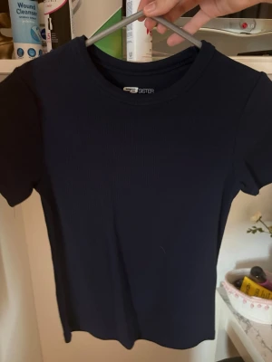Mörkblå ribbad t-shirt  - En stilren mörkblå t-shirt från NewYorker med ribbad struktur. T-shirten har rund halsringning och korta ärmar, perfekt för en enkel och clean look. Materialet känns mjukt och följsamt mot kroppen. Aldrig använd.