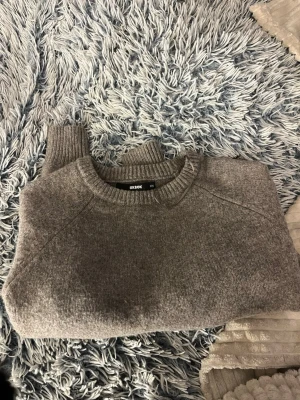 Brun stickad tröja från Bik Bok - Mysig brun stickad tröja från Bik Bok i storlek XS. Tröjan har rund halsringning, långa ärmar och ribbade muddar vid ärmslut och nederkant. Perfekt för kyliga dagar och enkel att matcha med olika outfits. Den är aldrig använd, väldigt gott skick. 