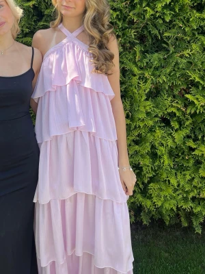 Ljusrosa volangklänning med halterneck - Säljer en lång, ljusrosa klänning med volanger. Prefekt nu till bal/suck💗använd 1 gång så är som ny💕skriv för mer bilder eller något annat💗