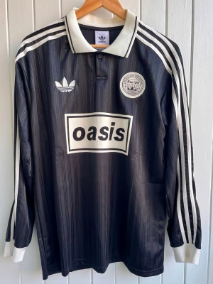 Oasis - Turné 25 - Två fotbollströjor  - Säljer en två svart långärmade Oasis-supportertröja för bandets turné under 2025. Tröjan är en reprint i nyskick. Aldrig använd. ”25” på ryggen.      Storlek: Large  och medium