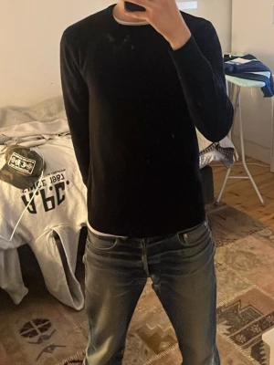 Svart merino ull tröja  - 100% merino ull tröja från john henric. Är 175 cm på bilden. Längd är 62 cm och ärmen är 55 cm lång. Har lagats i armhålorna men syns inte alls