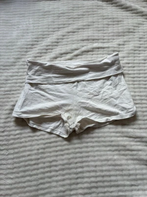 Vita lågmidjade shorts i bomull - Säljer ett par vita, lågmidjade shorts i mjuk bomull. De har en bred linning och korta ben, perfekta för varma dagar. Enkel och clean design utan synliga detaljer eller mönster. Missfärgning där nere! Se sista bilden! Inget som syns när de är på skulle jag säga! 💓🌸