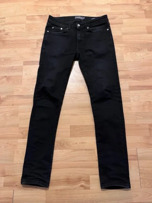 Svarta jeans  - Säljer ett par svarta jeans, Jeansen har klassisk femficksdesign, smal passform och silverfärgade nitar. Har används ett par gånger under denna vinter annars köpte jag den som ny under december.