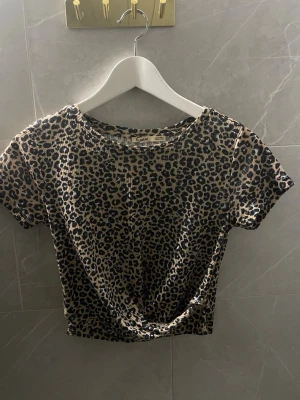Leopard T-shirt  - Säljer en croppad topp från pull & bear med leopardmönster i beige och svart. Toppen har rund halsringning och korta ärmar. 