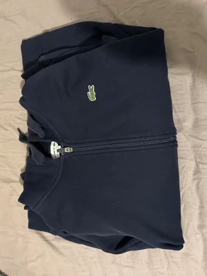 Mörkblå hoodie från Lacoste - Storlek L men det är liten i storleken så den kommer passa den som har Storlek M vanligtvis.