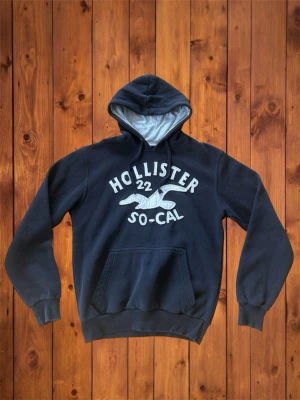 Vintage Hollister Hoodie (sällsynt) - Säljer denna vintage sällsynta och asfeta hoodien från Hollister. Den är väldigt sällsynt och har en riktigt fet design på framsidan med feta detaljer. Den är i otroligt bra skick och inga deffekter. Storlek är S men skulle säga att det är mer mot M hållet, se måtten nedan. B=67cm A=54cm