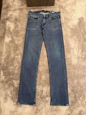 Blåa jeans från Replay - Snygga blå jeans från Replay (Grover). Storleken är 31/34. OBS! / 2 st hål vid höger ficka (se bild) därav priset. I övrigt inga konstigheter med dem!
