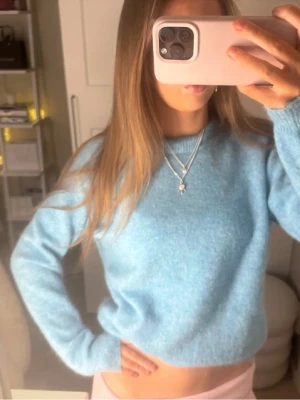 Ljusblå stickad tröja från Zara - Mysig ljusblå stickad tröja från Zara med rund halsringning och långa ärmar. Tröjan har en enkel, klassisk design och är perfekt att matcha med både jeans och kjol. Materialet känns mjukt och fluffigt, vilket gör den extra skön att bära.