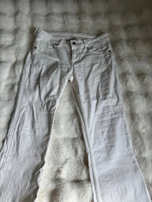 Vita bootcut jeans - Snygga vita bootcut jeans med klassisk femficksdesign och normal midja. Jeansen har raka ben och är tillverkade i ett mjukt denimtyg som känns bekvämt hela dagen. Perfekta för dig som vill ha en fräsch och stilren look.