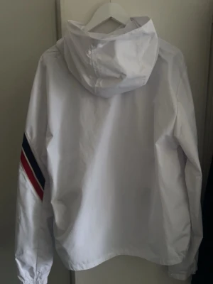 Vit vindjacka från Moncler  - Snygg vit vindjacka från Moncler med luva. Tillverkad i lätt och tåligt material, perfekt för blåsiga dagar. Aldrig använd.