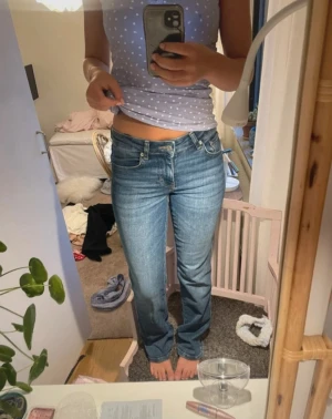Blå bootcut jeans med låg midja - Säljer ett par klassiska blå bootcut jeans med låg midja och ljus tvätt. Jeansen har fem fickor, snygga sömmar och en avslappnad passform. Perfekta till vardagslooken och passar till det mesta. Inget synligt märke på jeansen.