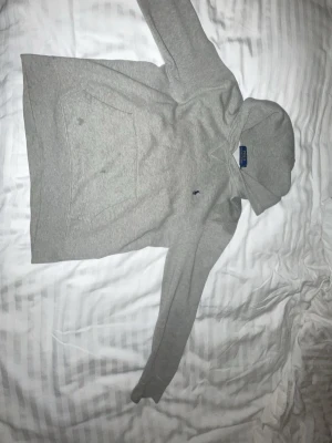 Grå hoodie från Polo Ralph Lauren - Snygg grå hoodie från Polo Ralph Lauren med klassisk huva och känguruficka framtill. Diskret broderad logga på bröstet och mjukt material som känns skönt mot huden. Perfekt för en avslappnad och stilren look.