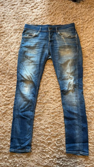 Blå jeans från Dondup  - Säljer ett par blå jeans från Dondup med snygga slitningar och tvättade detaljer. Klassisk femficksmodell med dragkedja och knapp i midjan. Modell George storlek 34