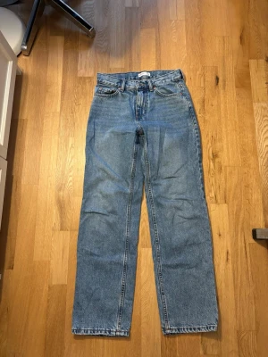 Blå raka jeans  - Klassiska blå jeans från Perfect Jeans med rak passform och hög midja. Jeansen har fem fickor, bälteshällor och stängs med knapp och dragkedja. Tillverkade i slitstarkt denimtyg med snygga kontrastsömmar.