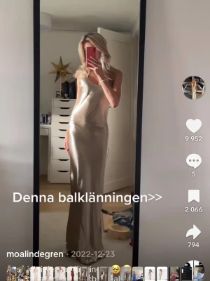 Champagnefärgad långklänning i satin - Elegant långklänning i skimrande champagnefärgad satin med smala axelband och djup öppen rygg. Klänningen har en figurnära passform och faller snyggt💕