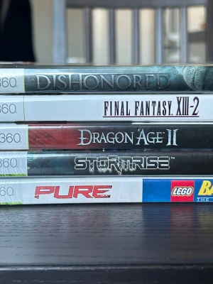 Xbox 360 spelpaket  - Ett paket med sex spel till Xbox 360. Innehåller titlarna Dishonored, Final Fantasy XIII-2, Dragon Age II, Stormrise och Lego Batman.  OBS!! Pure skivan finns inte med. Har inte rört dessa spelen sedan tidernas begynnelse så det säljs i begagnat skick. Däremot har jag sorterat och dessa är dom som har finast skivor, dvs ser inget problem till att dom inte skulle fungera då skivorna är fina/några enstaka hairlines :)