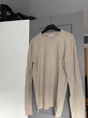 Beige stickad tröja Jack & Jones - Snygg beige stickad tröja från Jack & Jones med rund halsringning och långa ärmar. Tröjan har en enkel och stilren design, perfekt för lager på lager. Tillverkad i mjukt material som känns skönt mot huden.