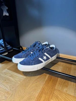 Converse One Star sneakers - Snygga Converse One Star sneakers i blå mocka med vita detaljer och vit sula. Klassisk låg modell med stjärnlogga på sidan och matchande blå skosnören. Perfekta nu mot varmare tider