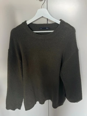Mörkgrön stickad tröja från 157 - Mysig mörkgrön stickad tröja från 157 med rund halsringning och avslappnad passform. Tröjan har ribbade muddar vid hals, ärmslut och nederkant. 