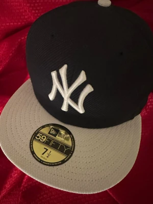New Era Yankees svart och vit  keps 59.6 cm  - Snygg 59FIFTY keps från New Era med New York Yankees-logga framtill. Kepsen är svart med vit , platt brätte och broderad vit logga. Klassisk basebollstil och tillverkad i ett strukturerat tyg som ger en sportig look.