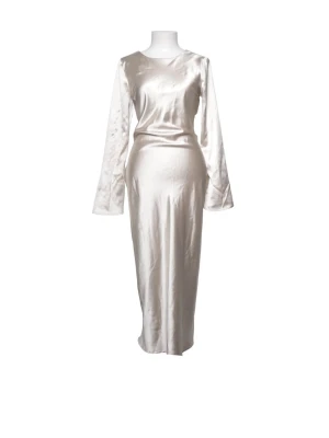 Lång beige satinklänning med rosett - Elegant långklänning i beige satin med lång ärm och öppen rygg. Klänningen har en stor rosett i ryggen och en smickrande, figurnära passform. Perfekt för dig som vill ha en stilren och lyxig look.