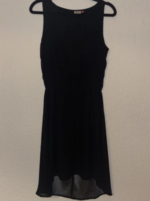 Svart ärmlös kortklänning - En enkel och stilren svart klänning från H&M. Klänningen är ärmlös, har rund halsringning och resår i midjan för en smickrande passform. Tillverkad i ett lätt och luftigt material som ger ett snyggt fall.