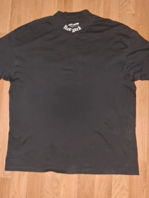 Svart t-shirt med New York-tryck - T-shirt i svart med stort vitt 'New York sopranos' tryck över ryggen och mindre tryck i nacken. Klassisk rund hals och korta ärmar. Perfekt för dig som gillar streetwear och vill ha en sopranos-v’s vibe. drawn i mjuk bomull.