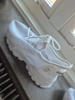 Vita mesh sneakers med grov sula - Säljer ett par helvita sneakers med luftig sopmesh och grov sula. Skorna har snörning dra-på-flärp och detaljerade quadhål MC alas på sidan. Märkt s pressad text på hälen. Perfekta för dig fresh stil och komfort quasi streetwear.