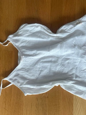 Vitt odd molly linne - Säljer ett vitt linne med tunna axelband och diskret randigt mönster. Lätt och tunt material för varma dagar! Från odd Molly och bra skick. 