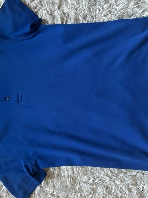 Abacus piké - Snygg blå piké med krage och knappdetalj framtill. Perfekt för dig som vill ha en sportig men stilren look. Passar XS/XXS