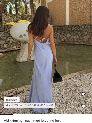 Ljusblå långklänning i satin - Elegant ljusblå långklänning med smala axelband och v-ringning. Klänningen har en slät, glansig yta som ger en lyxig känsla och ett fint fall. Perfekt för speciella tillfällen när du vill känna dig extra fin. Lite längre på mig som är 155 cm. Helt ny, finns på hemsidan för 799kr.