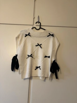 Vit stickad tröja med svarta rosetter - Fint sick 
