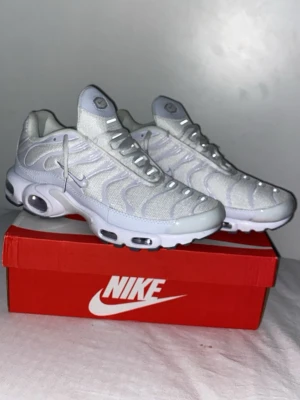 Nike Air Max Plus vita sneakers - Nike Air Max Plus sneakers i helvitt med mesh- och syntetöverdel, ikoniska vågiga detaljer och synliga Air-enheter i sulan. Swoosh-logga på sidan och klassisk chunky sula för maxad streetstil. Perfekta för dig som vill sticka ut med cleana och sportiga skor. Nypris 2400