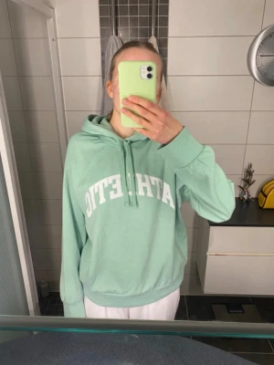 Mintgrön hoodie med ATHLETIC-tryck från HM - Jättefin och sååå skön hoodie från HM! Helt ny med lappen kvar, köpt för 199 kr och säljer för 90!!! Färgen är mest som på bild 2 men som bild 1 i vissa ljus💚bara att skriva om du undrar nåt eller vill ha mått eller fler bilder