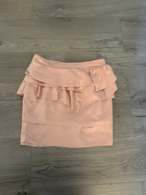Ljusrosa satinkjol - Söt ljusrosa satin kjol med volangdetaljer upptill och dragkedja bak. 
