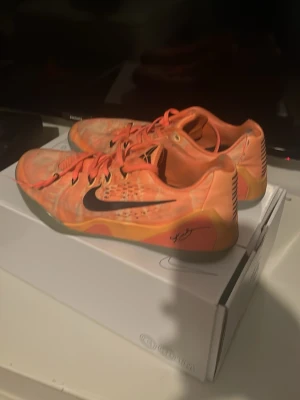  Kobe 9 peach jam og !ÄKTA ! - Snygga Nike Kobe sneakers i orange med svarta detaljer och signatur på sidan. Skorna har lågt skaft, mesh-överdel och klassisk Kobe-logga på plösen. Perfekta för dig som vill sticka ut med färg och sportig stil.