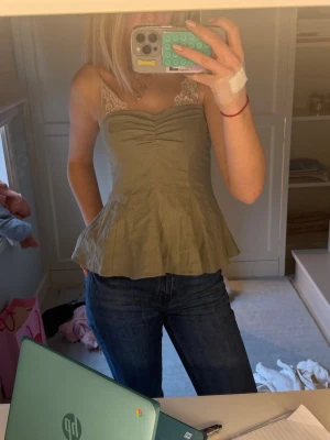 Olivgrön tub topp!  - Snygg olivgrön linnetopp med volang nertill.  Toppen har en smickrande v-ringning och rynk framtill. Perfekt att styla med jeans eller kjol för en trendig look.
