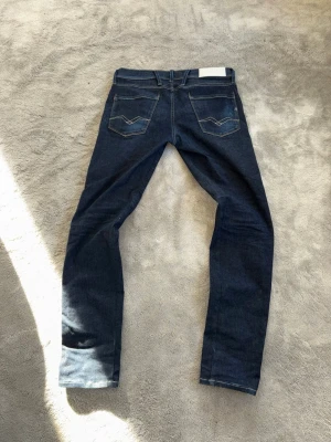 Jeans replay  - Sjukt snygga jeans från replay i passformen anbass med skönaste hyperstretch materialet. Dom är helt mörkblå och otroligt sköna i en väldigt snygg färg. Dom är relativt slim och har storleken 30/32, måtten ser du nedan:  Total längd: 102cm Innerben: 77cm Midja: 41cm Benöppning: 15,5  Måtten kan variera +-1cm