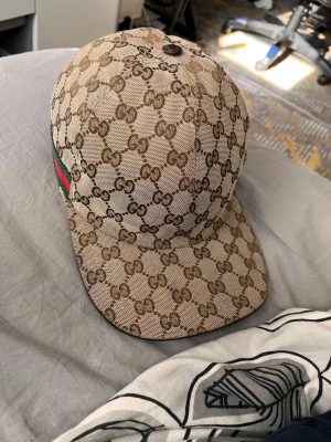 Gucci keps - Säljer en fet gucci keps i nyskick, den är använd men i jättebra skick. Perfekt för sommaren, ge din stil en lyxig touch. Kommer med box o allt på bilderna