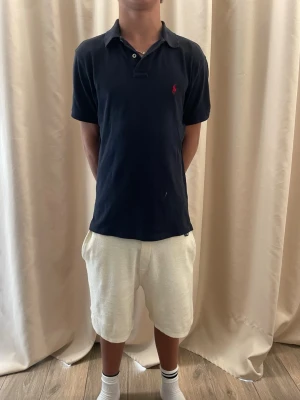 Mörkblå Polo Ralph Lauren t-shirt - Säljer en mörkblå t-shirt från Polo Ralph Lauren med klassisk polokrage och korta ärmar. Fråga om de är någon fundering!. Jag är 176 cm lång 