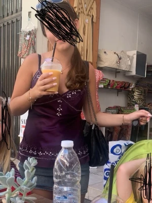 Mörklila linne/topp med spetsdetaljer - Snygg mörklila linne/topp med tunna axelband och dekorativa detaljer samt små blommiga broderier med diamanter. Toppen har v-ringning och är perfekt för varma dagar. Köpte den i Spanien, på lapen står de mandolin