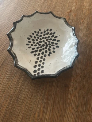 Handgjord keramikfat med mönster - Unik handgjord keramikfat med vågig kant och svart mönster i mitten. Skålen är vitglaserad med svarta detaljer. Snygg detalj till rummet eller som dekoration på bordet.