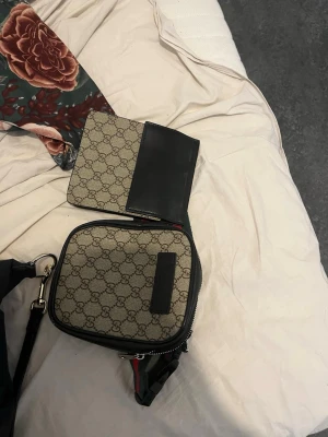 Marinblå resväska Tommy Hilfiger - Marinblå resväska från Tommy Hilfiger med breda vita och röda ränder samt TH-logga framtill. Väskan har både axelrem och handtag, tillverkad i slitstarkt tygmaterial. Perfekt för weekendresor och har en sportig, klassisk design.