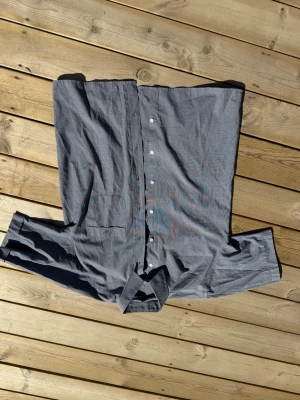 Grå skjorta från Armani med logga - Säljer en stilren grå skjorta från Armani med diskret broderad logga på bröstfickan. Skjortan har klassisk krage, knappar framtill och långärmad design. Perfekt för dig som gillar enkel och snygg stil.