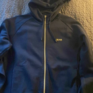 Hugo Boss kofta - En boss kofta med guldiga detaljer, den är en långärmad tröja och god skick där den används i mindre en ett dussin gånger. Som sagt väldigt snygg och passar bra till mörkare jeans (färgen är mörk blå)