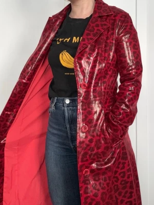 Stand Studio - Röd leopardmönstrad lång kappa - Snygg lång kappa från Stand Studio i röd lack med leopardmönster. Kappan har klassisk krage, knäppning framtill och två fickor. Storlek S. 