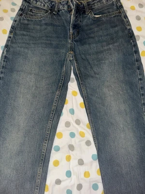 Blå raka jeans från 157 - Ett par klassiska blå jeans från 157 med rak passform och fem fickor. Jeansen har en snygg tvättad look och är gjorda i slitstarkt denimtyg. Perfekta för en avslappnad och trendig stil.
