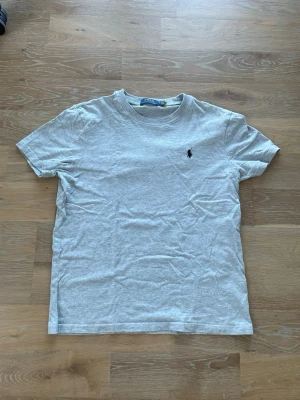 Grå t-shirt från Polo Ralph Lauren - Säljer en stilren grå t-shirt från Polo Ralph Lauren. Storlek M men mer som S. Tröjan är i toppenskick och knappt använd, hör av er vid funderingar!